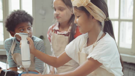 Little-Asian-Girl-Using-Hand-Blender-during-Culinary-Lesson